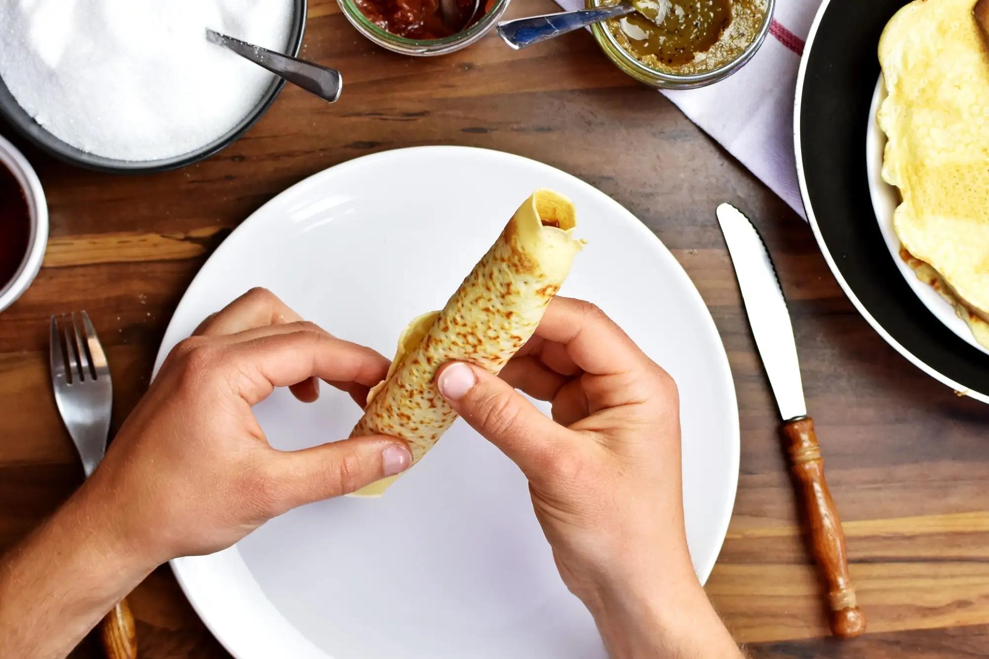 Mužské ruce rolující domácí palačinku.